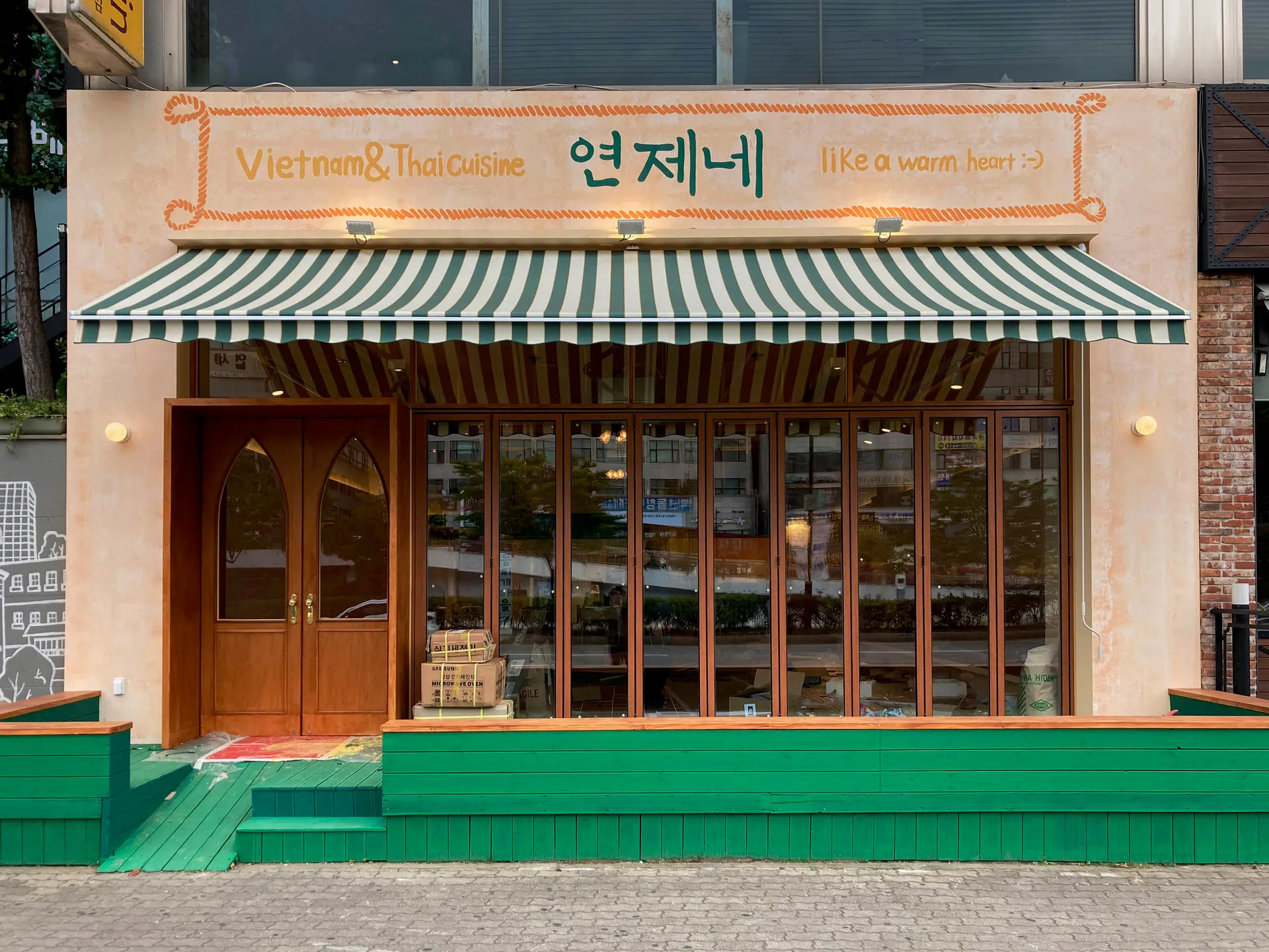 연제네 초록 줄무늬 차양과 아치 출입문이 있는 정면 외관