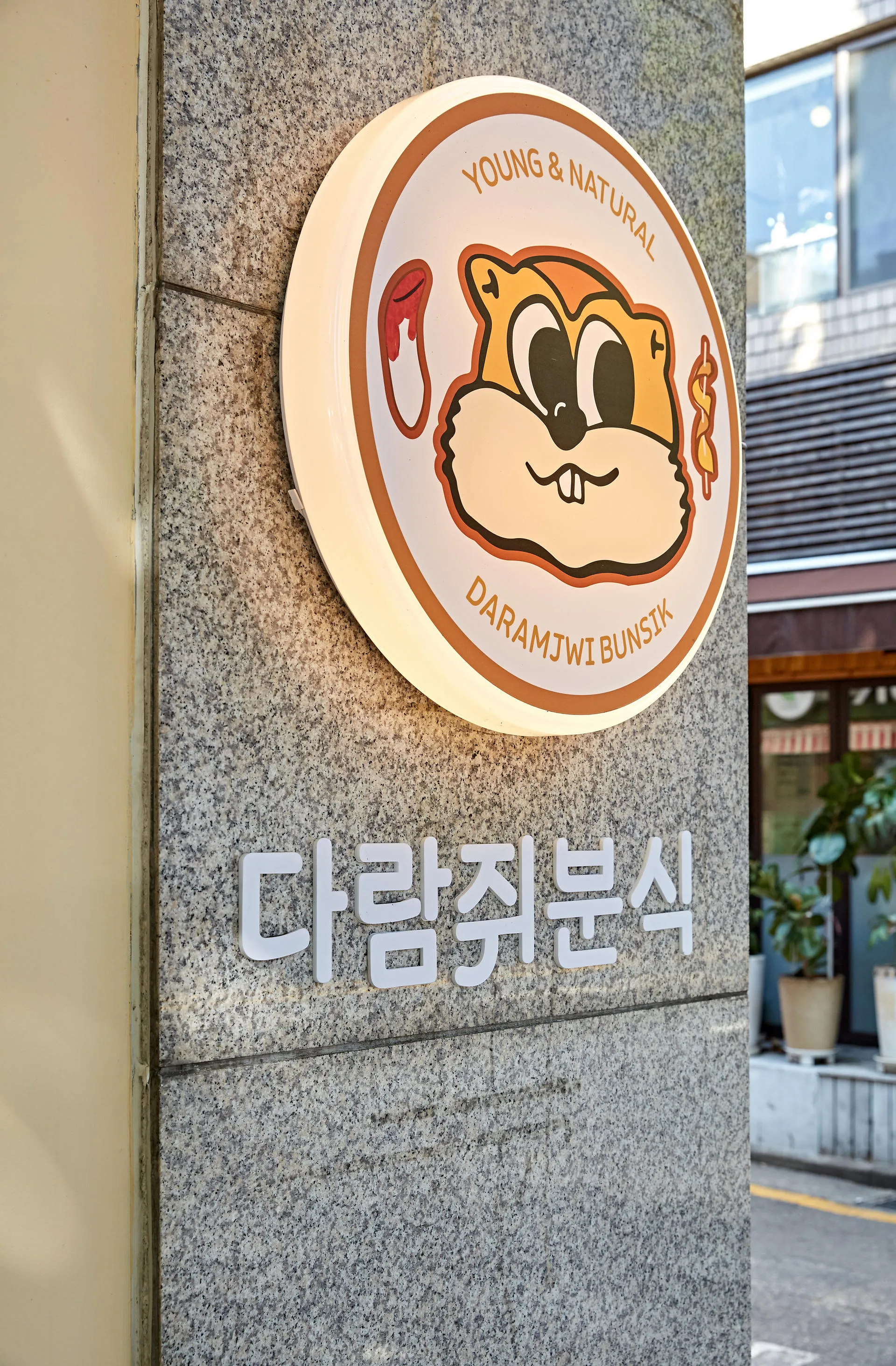 다람쥐분식 석재 외벽에 붙인 원형 로고 사인과 상호