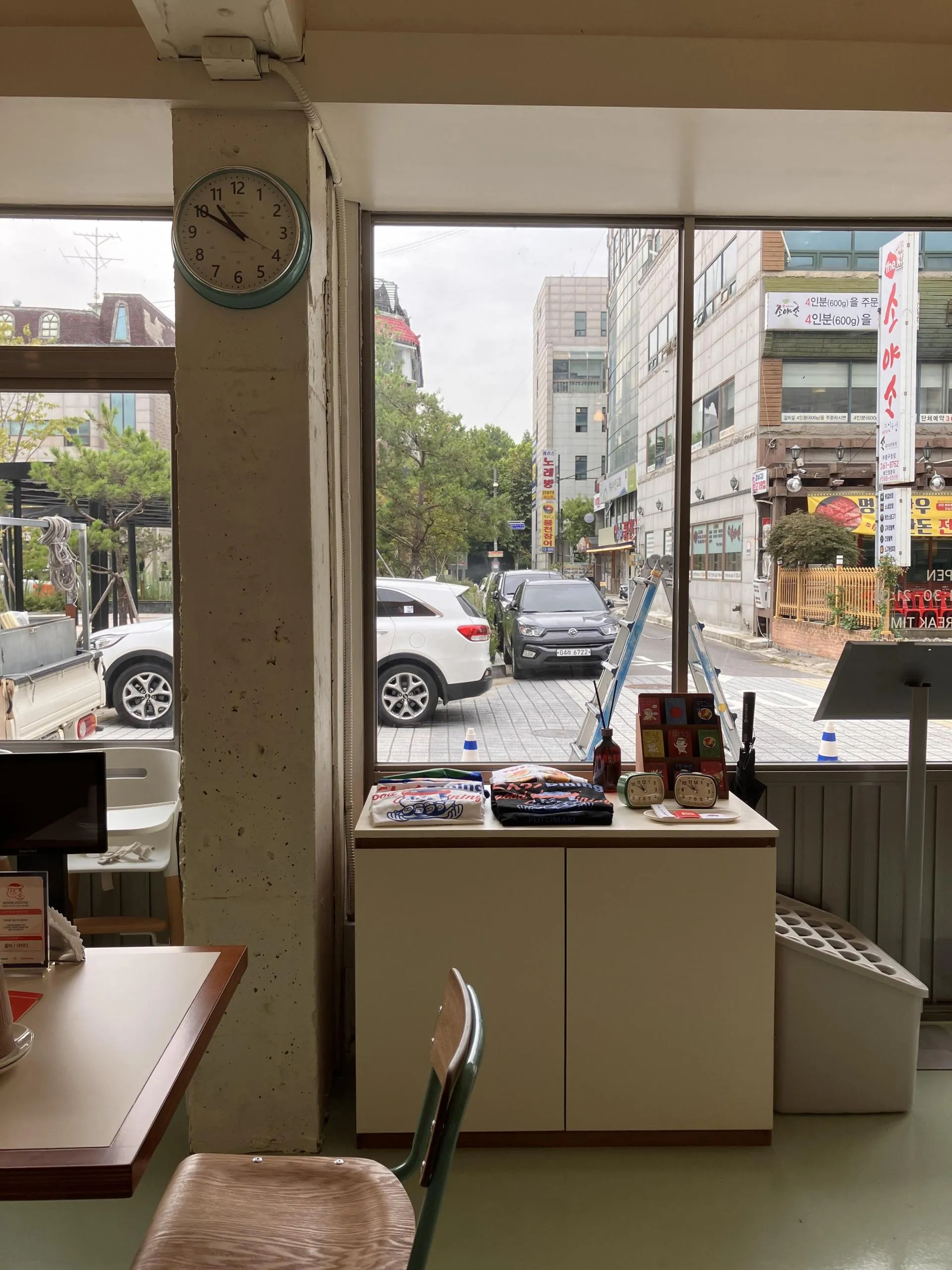 초이다이닝 부평점 통창 앞 굿즈 진열대와 벽시계