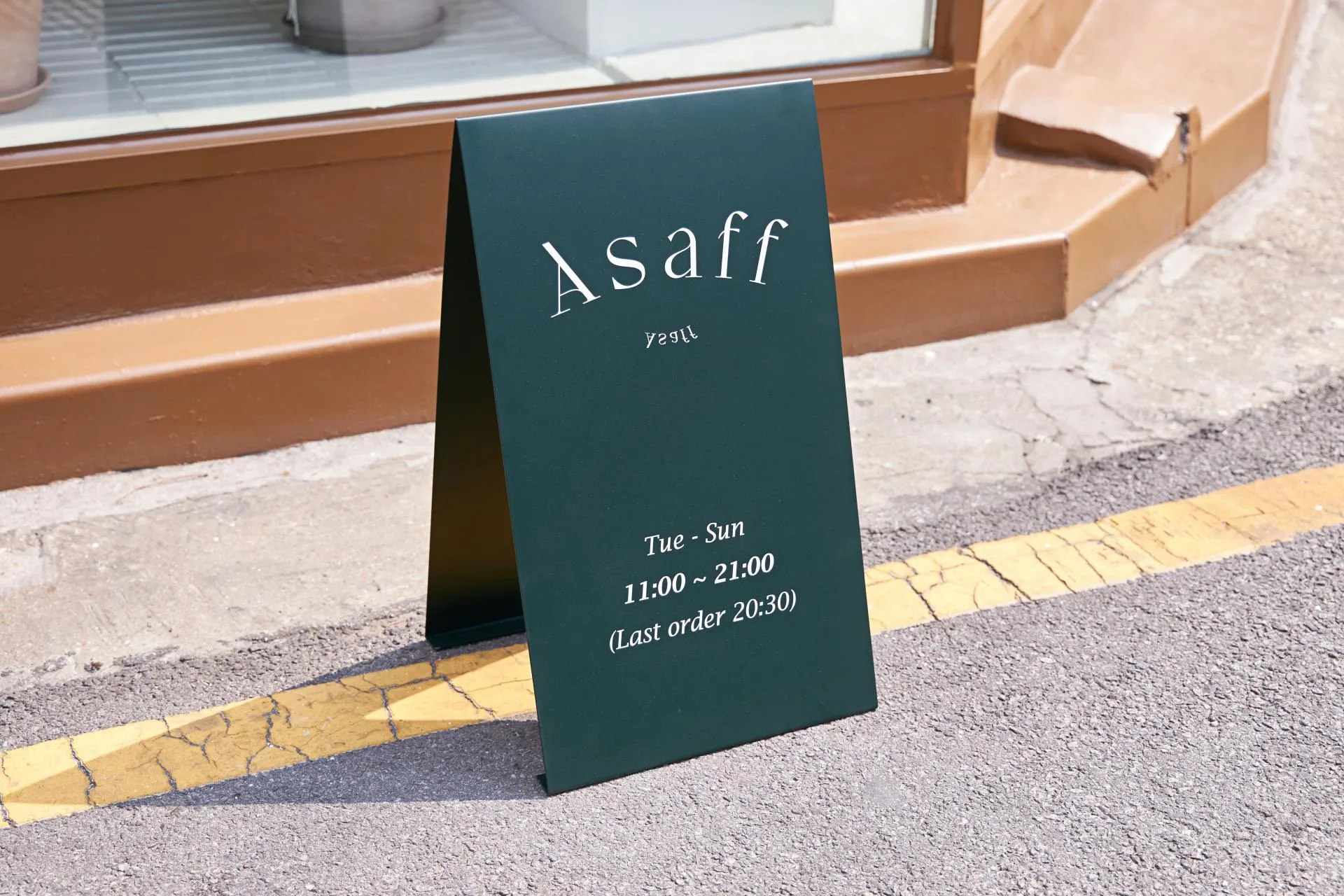 아사프 카페 영업시간이 적힌 짙은 녹색 입간판